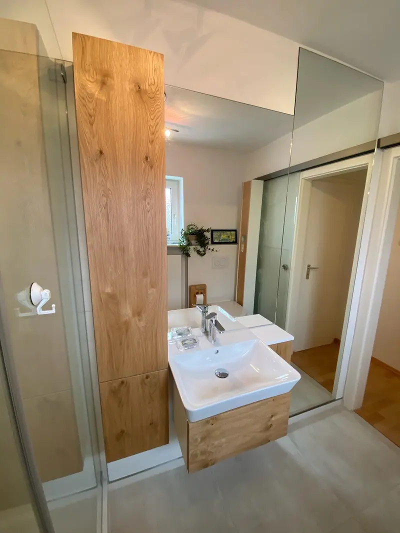 Badezimmer mit Waschtisch auf einem Unterschrank und Holzelement